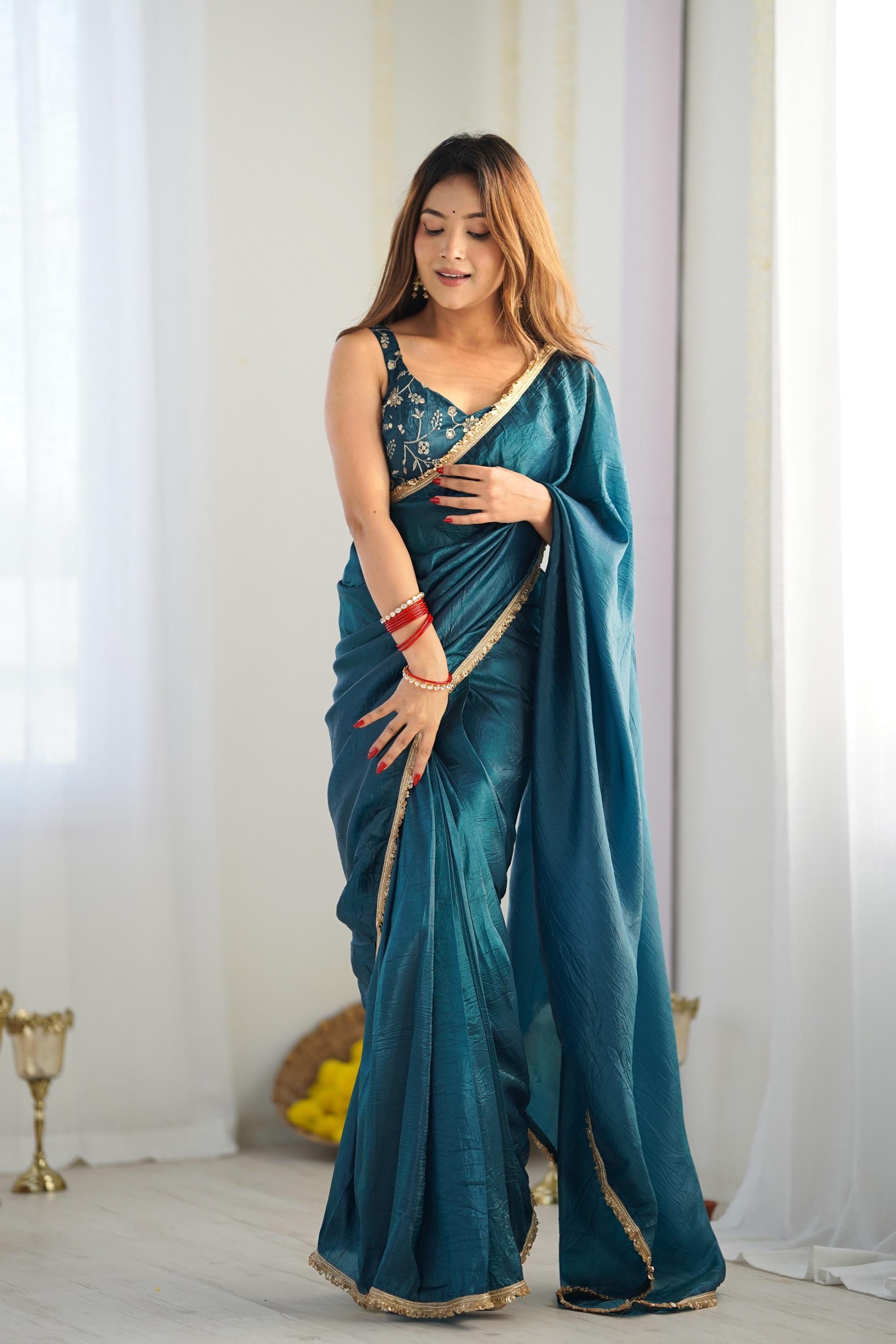 A woman elegantly draped in a turquoise ready to wear pre stitched saree features intricate embroidery