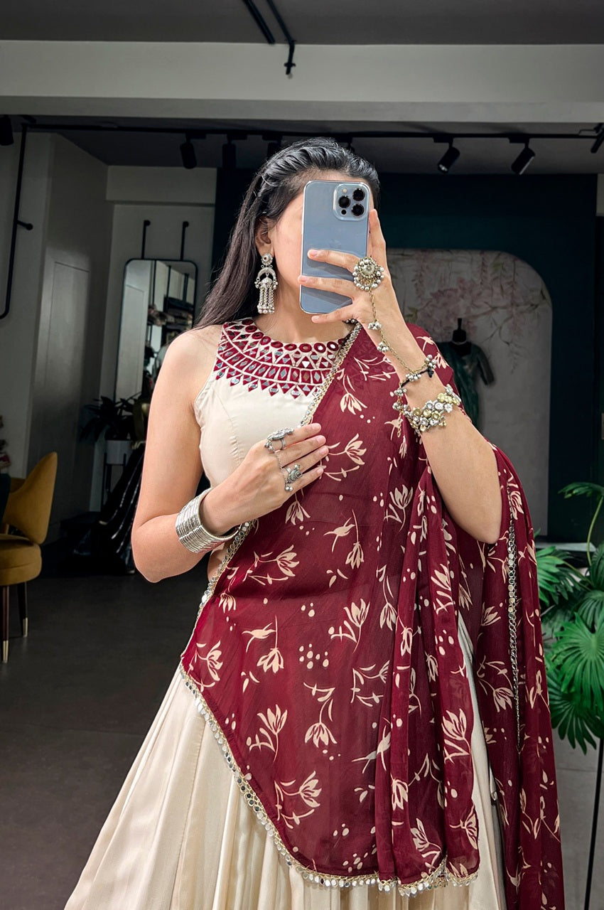 A woman takes a mirror selfie wearing a traditional Indian outfit consisting of a cream-colored dress with a heavily embroidered neckline and a deep maroon dupatta featuring a cream floral pattern.