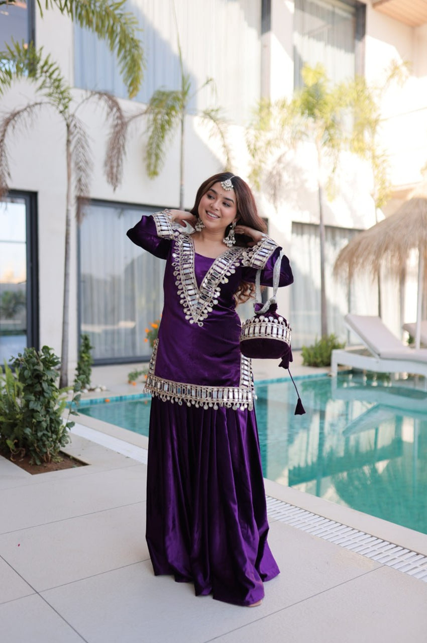 Woman in a purple traditional outfit with silver details standing by a pool.