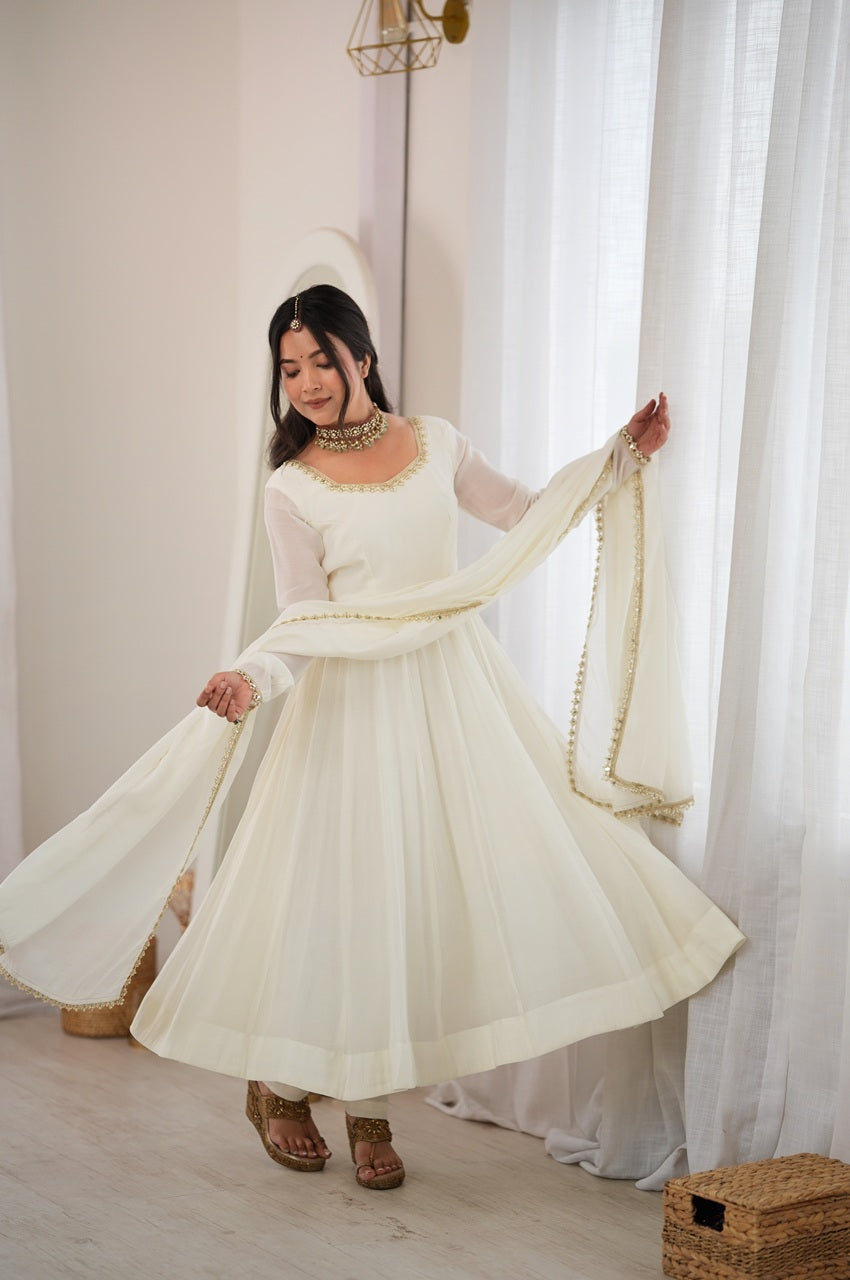 A woman wearing a traditional white Anarkali-style dress with a matching dupatta and headpiece