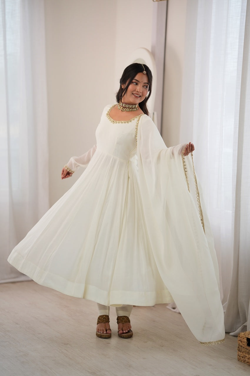 A woman modeling a traditional white Anarkali-style dress with a matching sheer dupatta and gold trim