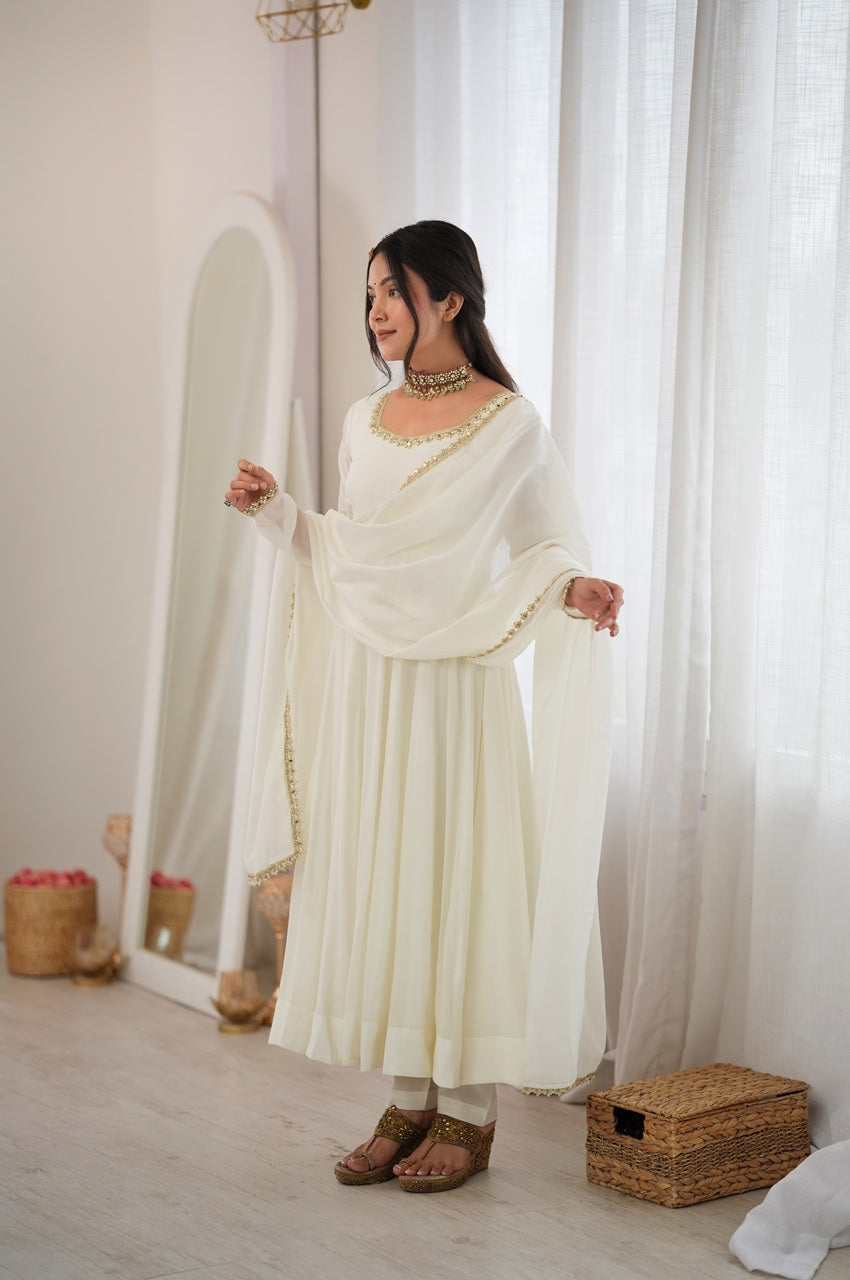 A woman modeling a cream-colored traditional outfit with a matching draped shawl