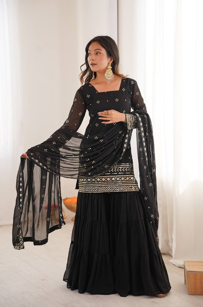 Woman wearing a black traditional outfit with gold embroidery in a minimalistic setting